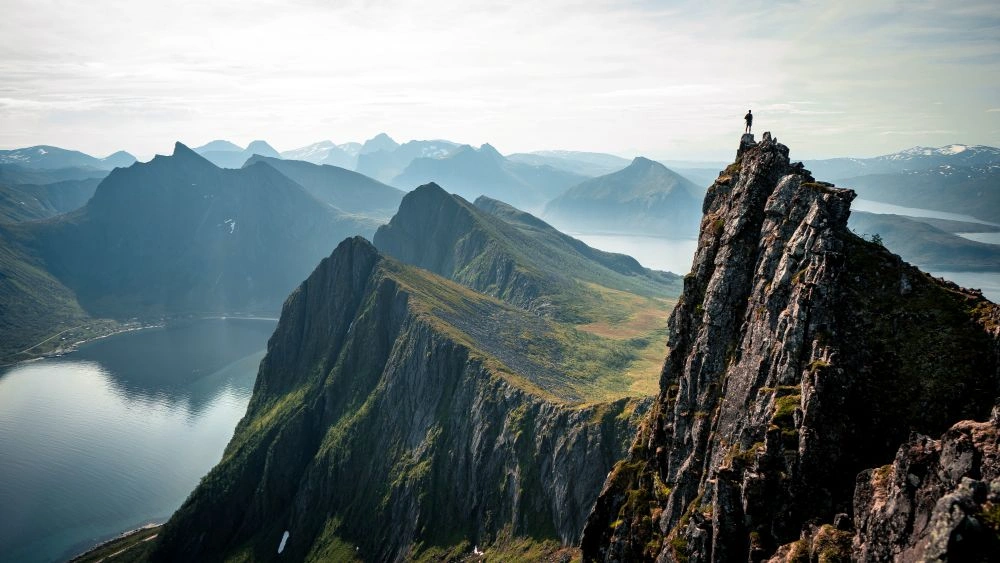 people standing on a mountain overlooking a valley and water